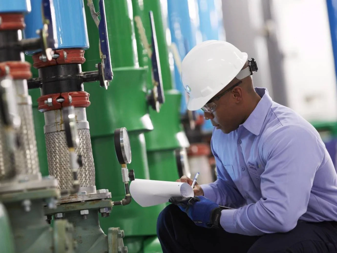 HVAC mechanic wearing a hard hat and recording equipment readings