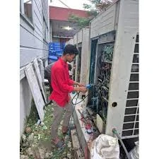 Technician inspecting outdoor HVAC equipment beside a building